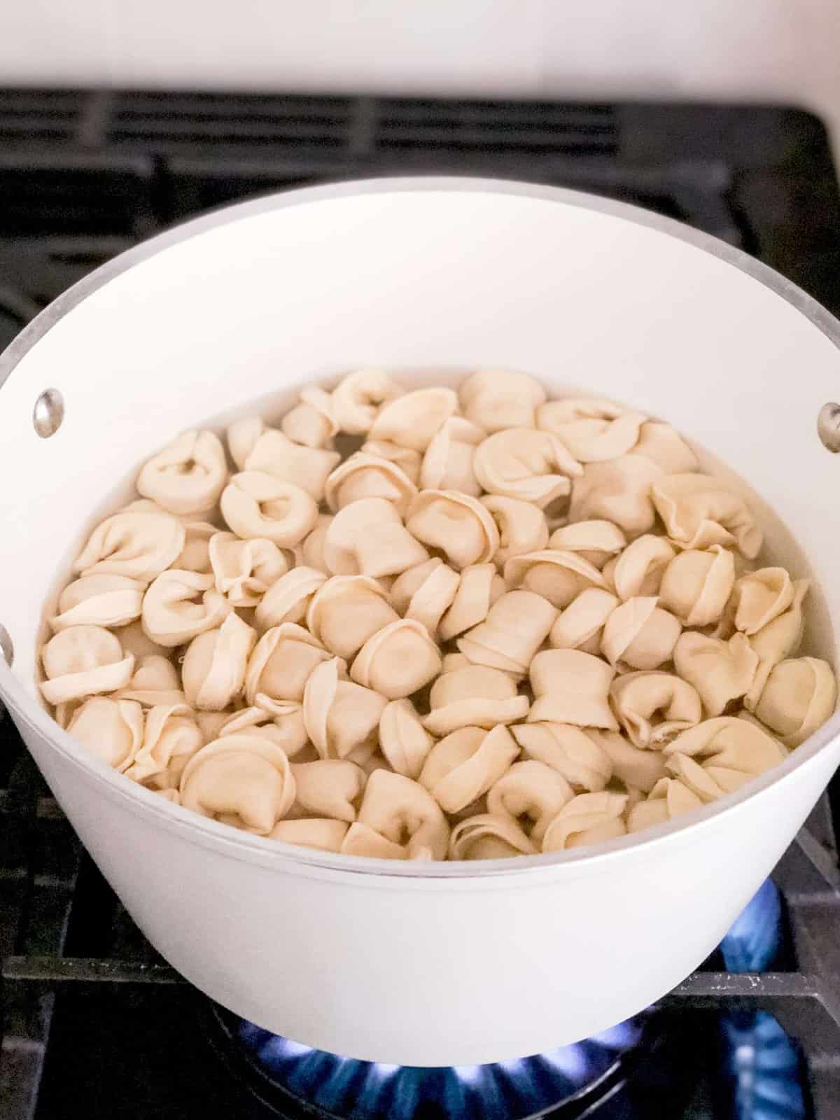 Chicken tortellini cooking on a stove.