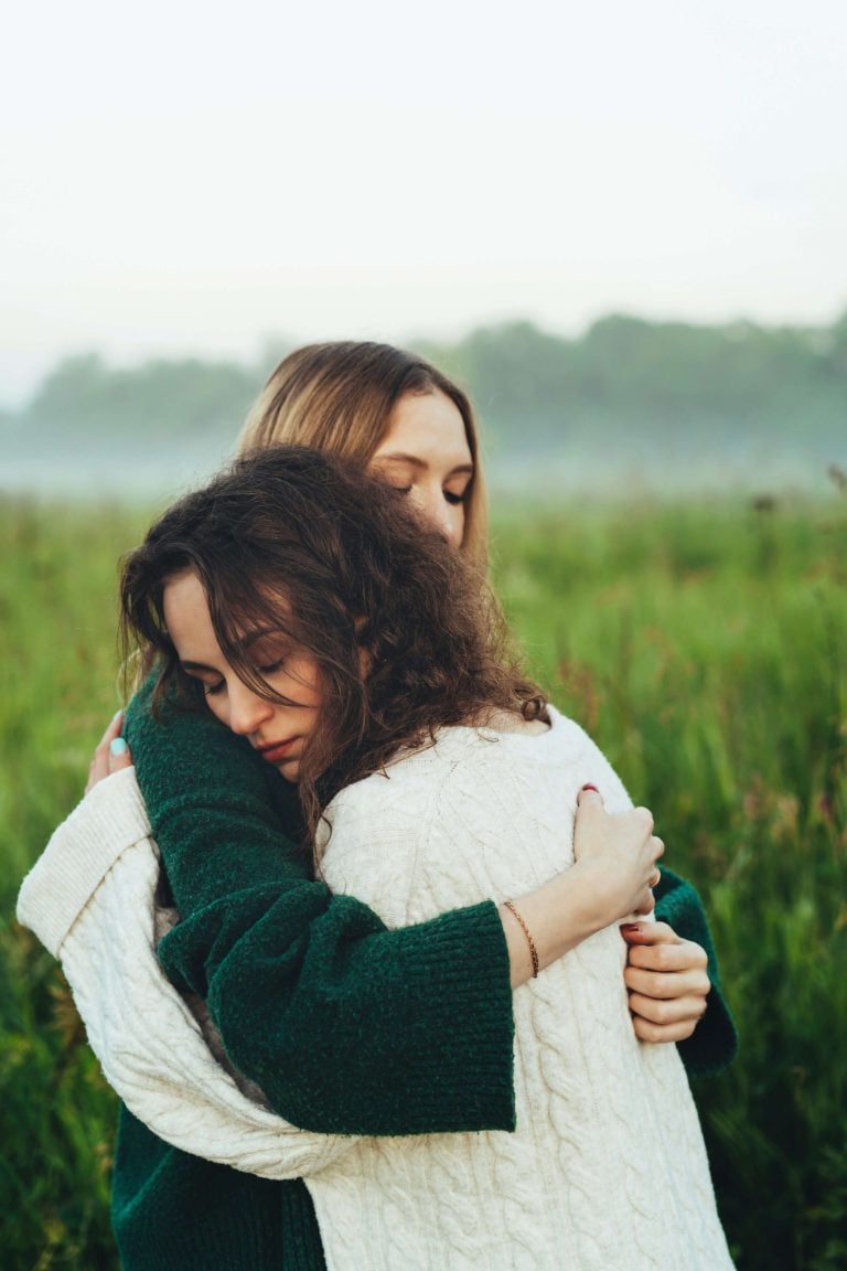 Two women hugging in a field.