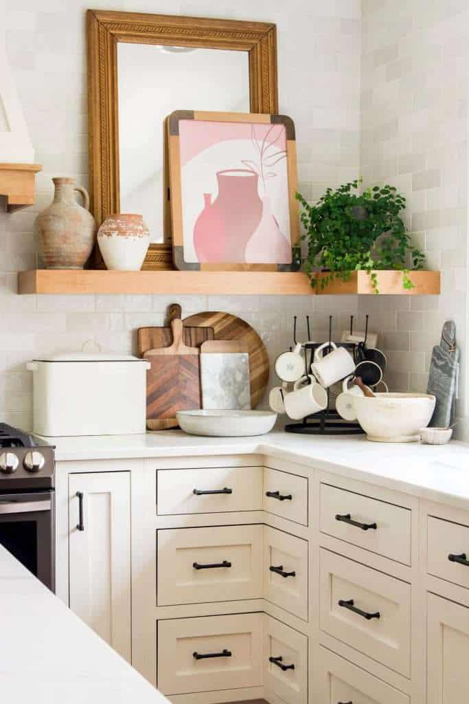 Kitchen shelves with artwork and plants.