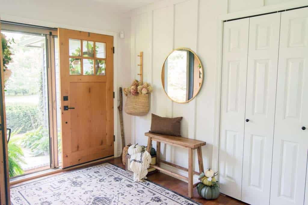 Brass mirror in an entryway decorated for fall.