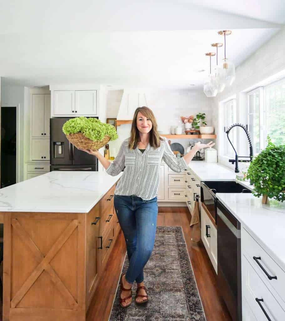 Woman holding dried hydrangeas in a kitchen.