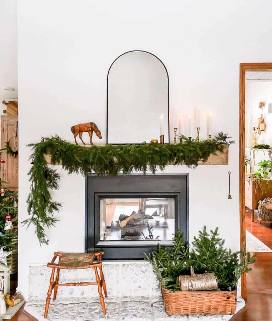 Black arched mirror on a fireplace mantel.