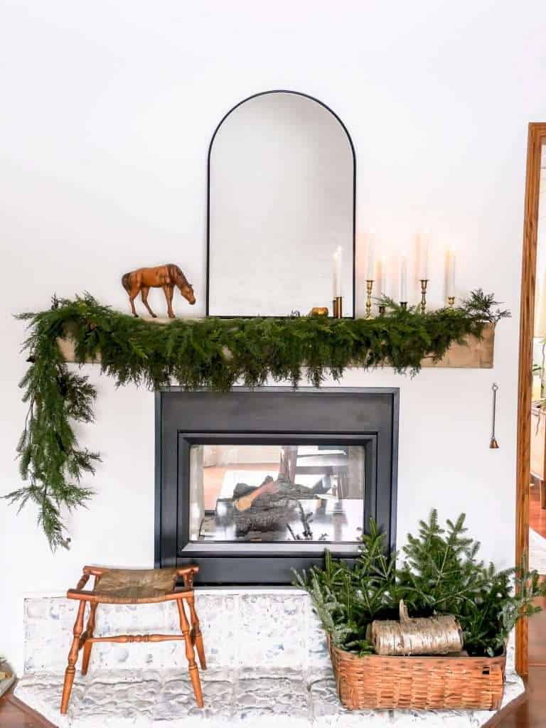 Winter mantel decor with garland and candles.