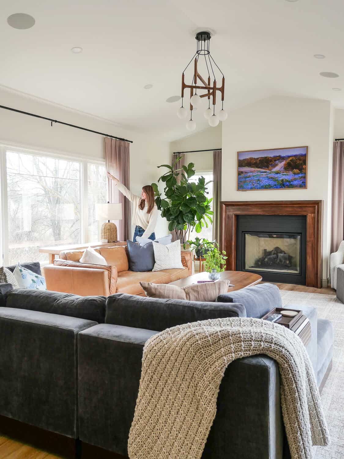 Woman opening curtains in a living room decorated for spring.