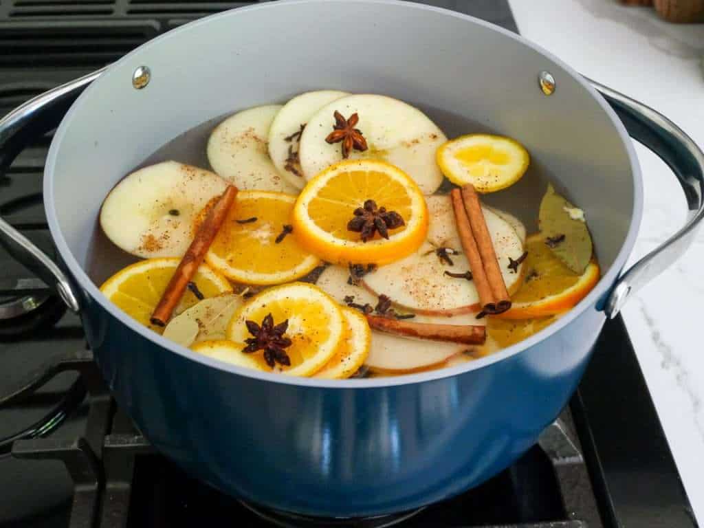 Pot on a stove with fruit and spices.