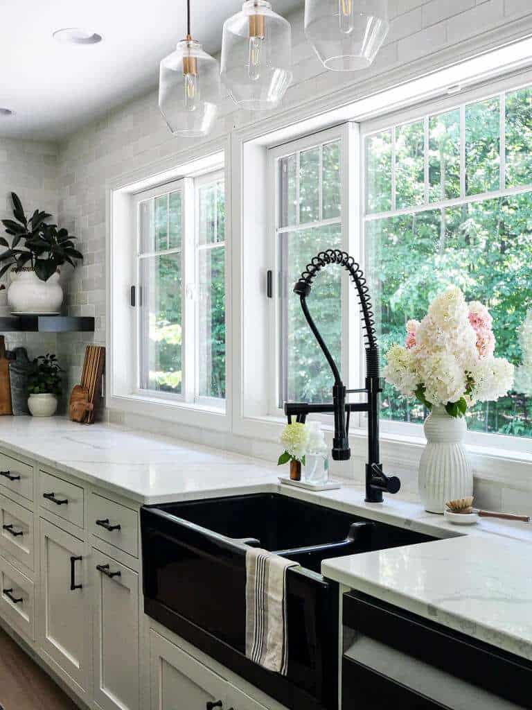 Kitchen with black sink and white countertops.