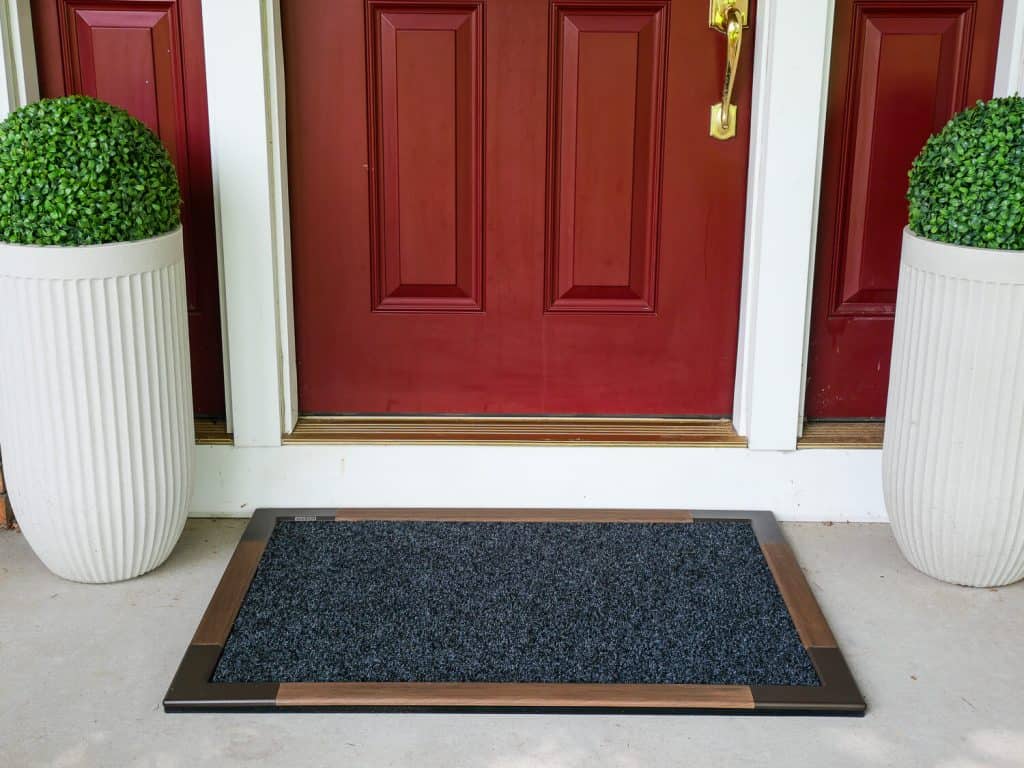 Outdoor mat with teak border and red front door.