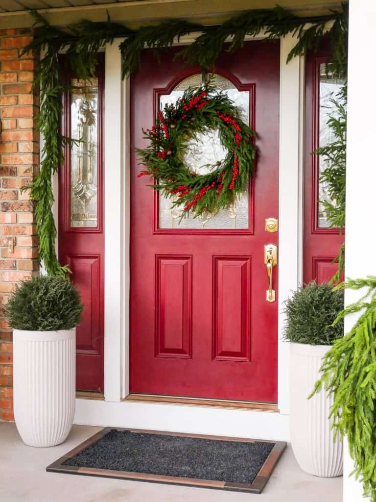 Red front door decorated for Christmas.