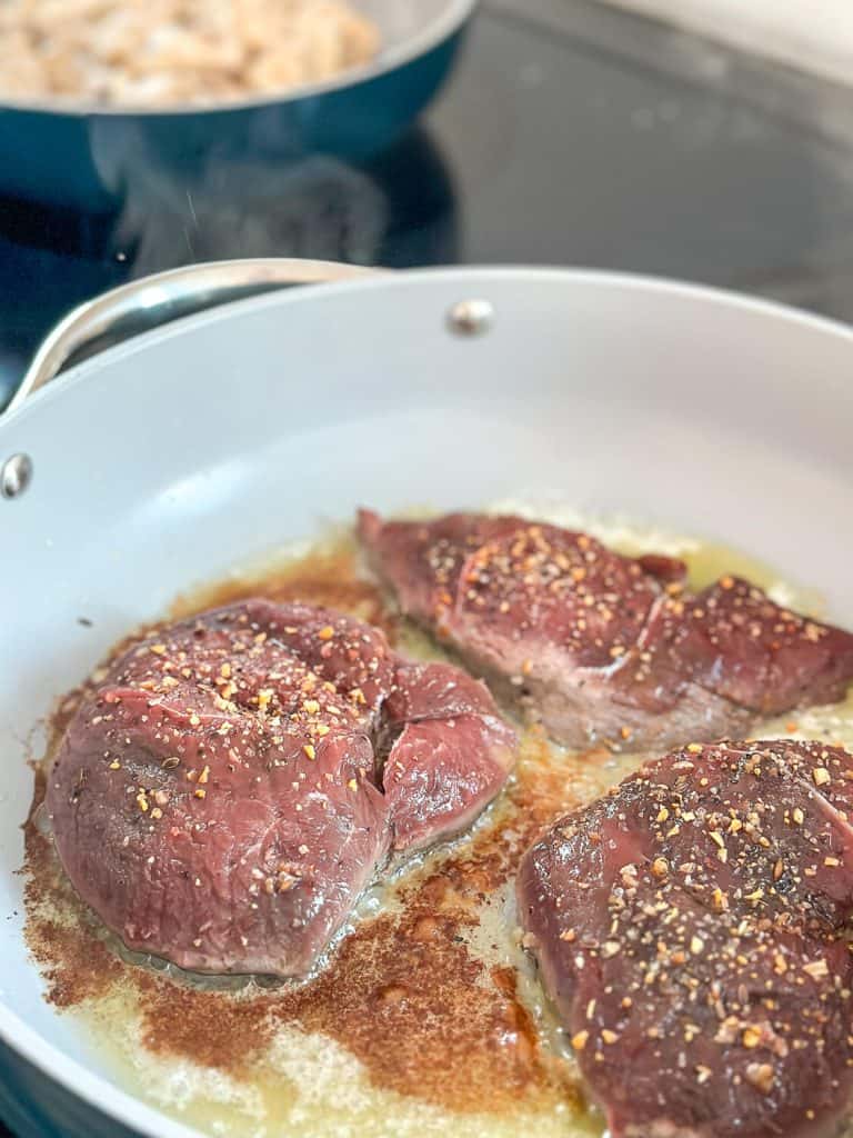 Searing venison in a skillet.