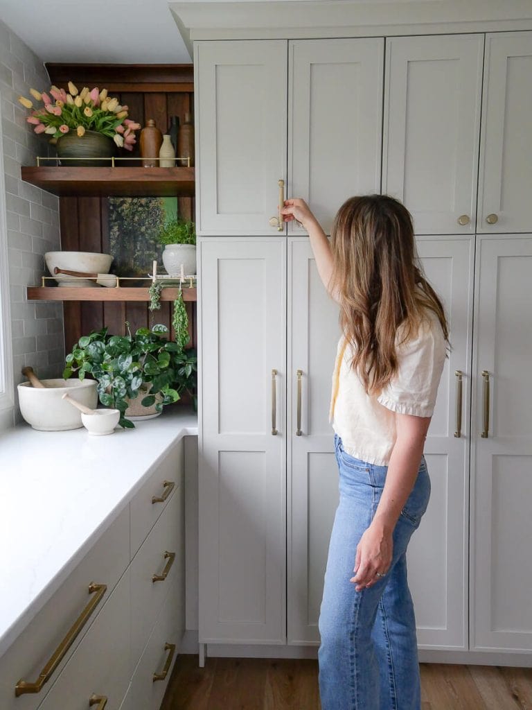 Woman holding a handle on the pantry.
