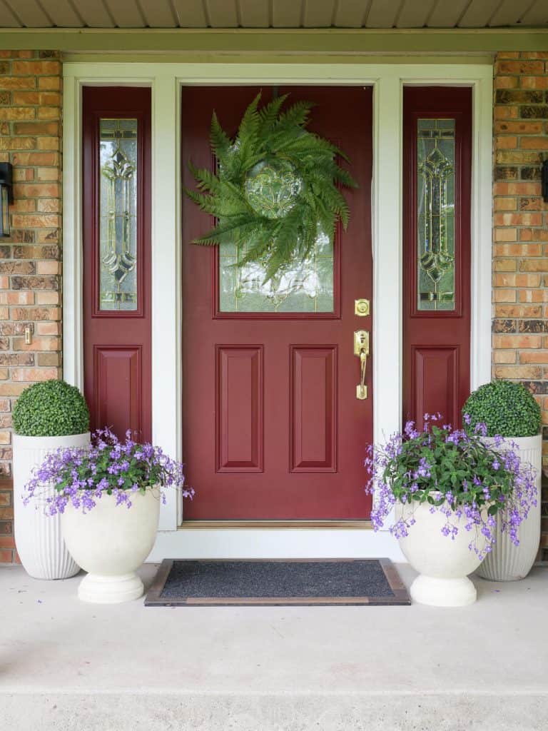 Faux potted plants by a red front door.