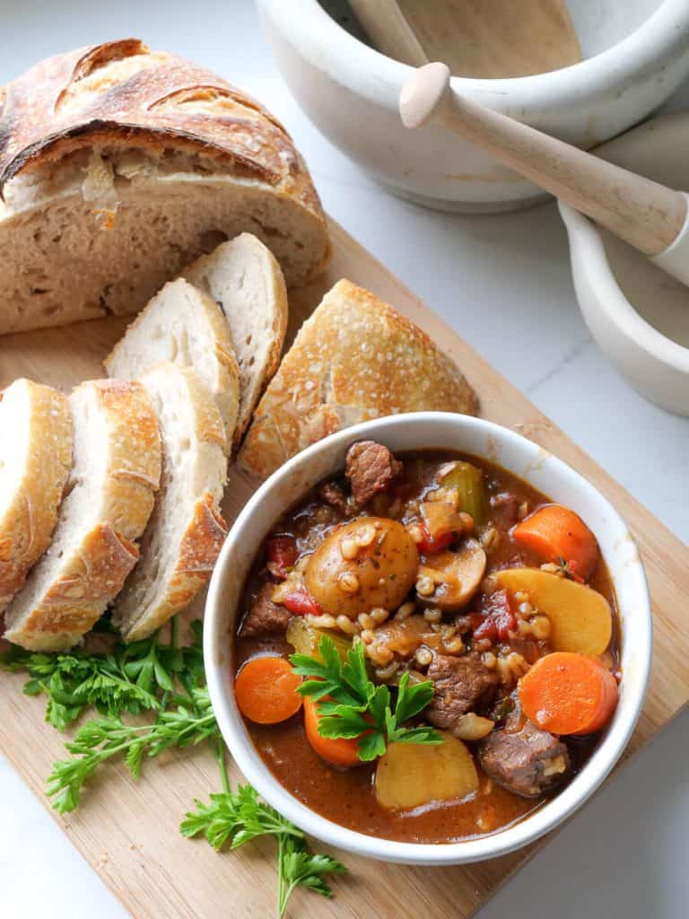 Beef barley stew with loaf of sourdough.