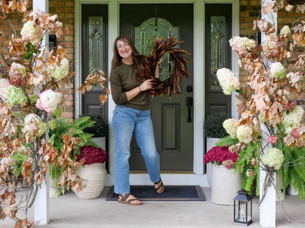 Woman standing in front of a fall front porch display.