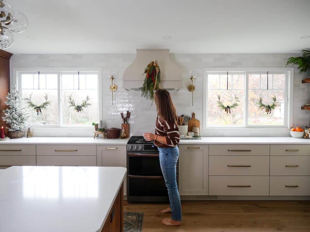 Woman placing a swag on the kitchen hood.