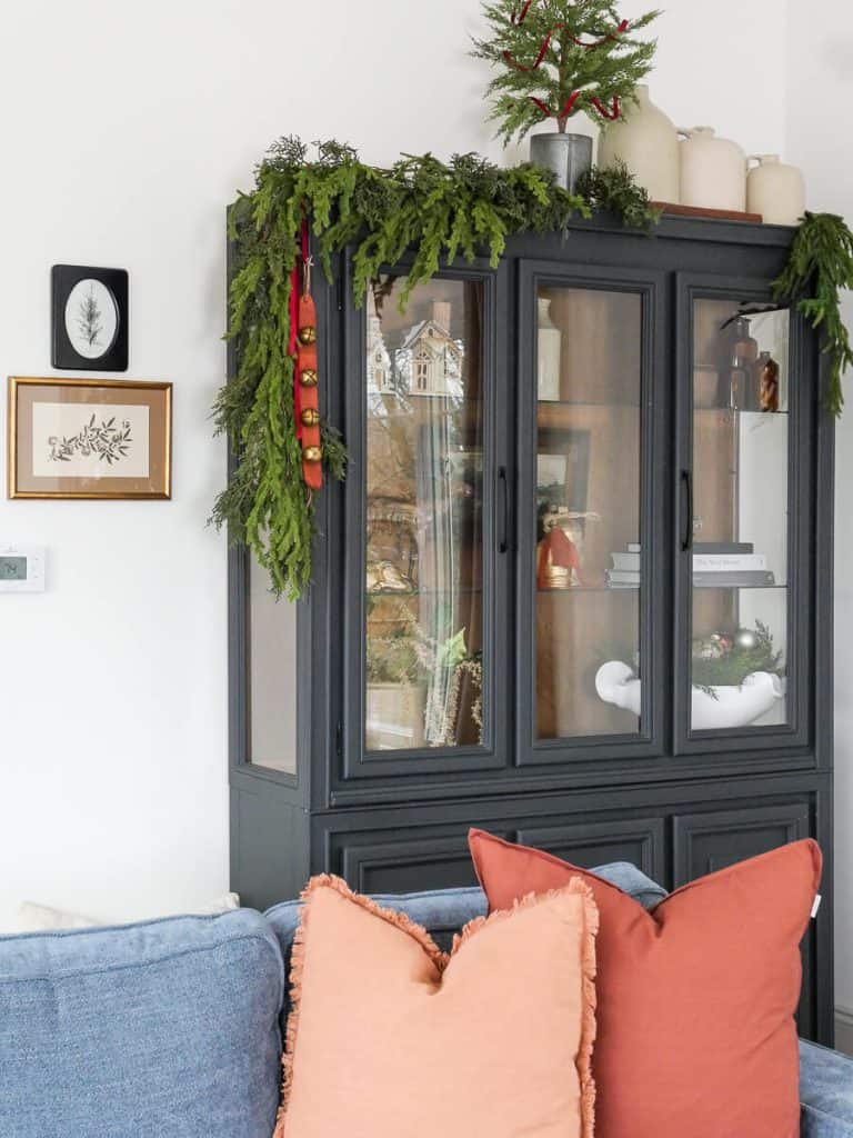 Black cabinet with garland and pillows.