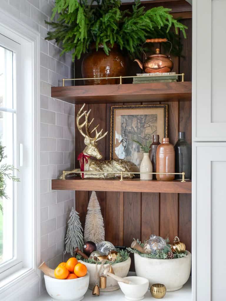 Norfolk pine branches on kitchen shelves with Christmas decor.