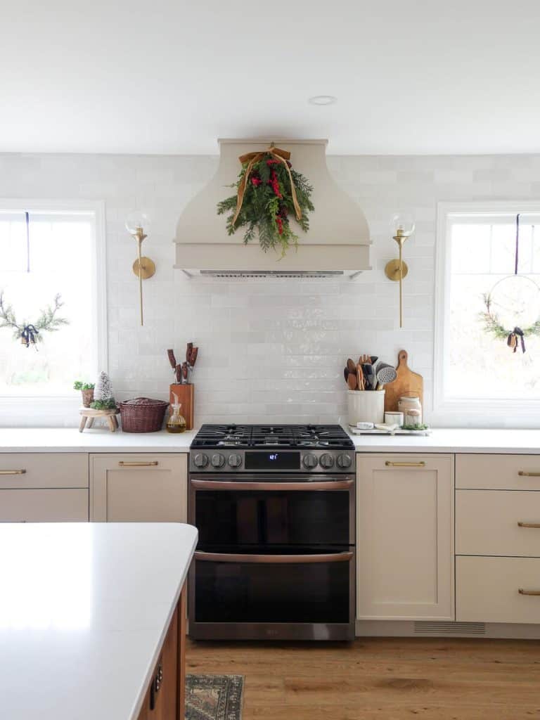 Swag on a kitchen hood with simple Christmas decorations on the windows.