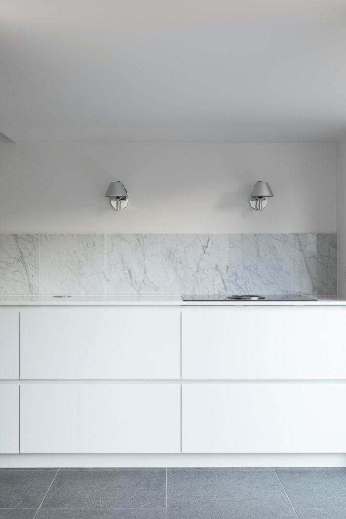 Grey stone backsplash in a white kitchen.