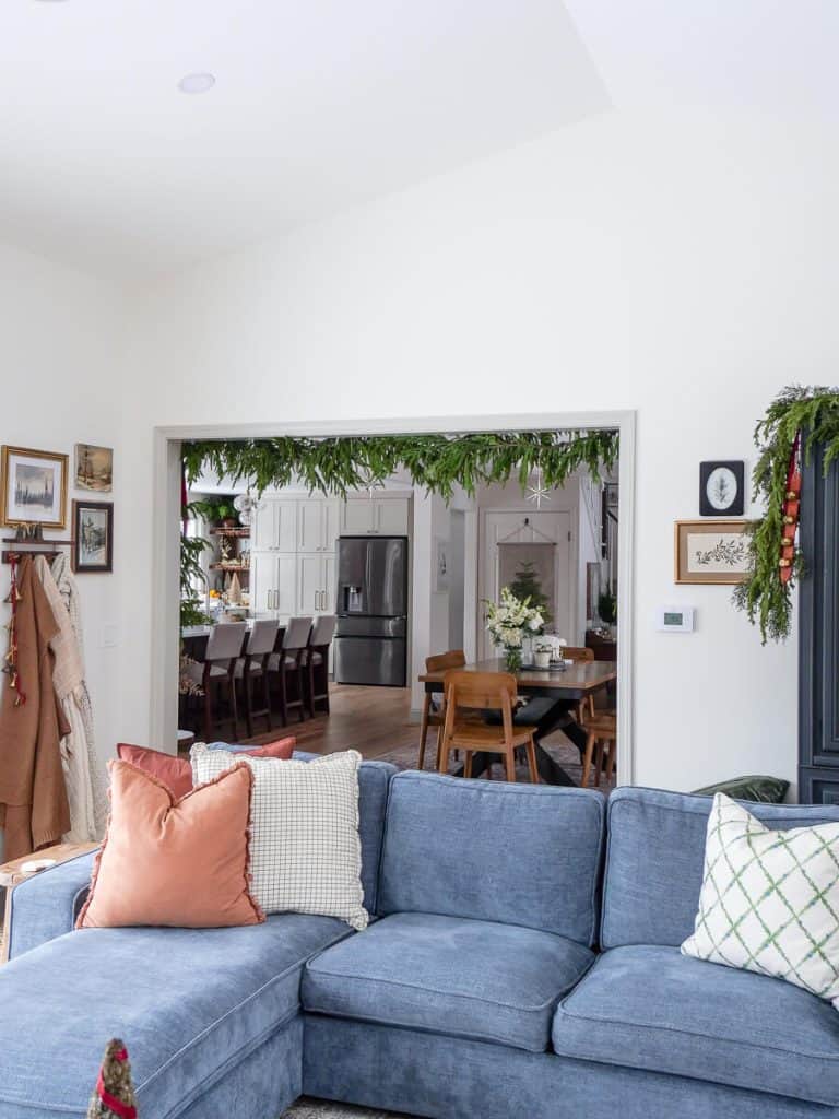 Blue sofa with pine garland and blankets hanging on a wall.