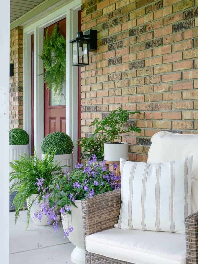 front porch furniture next to potted plants and the front door