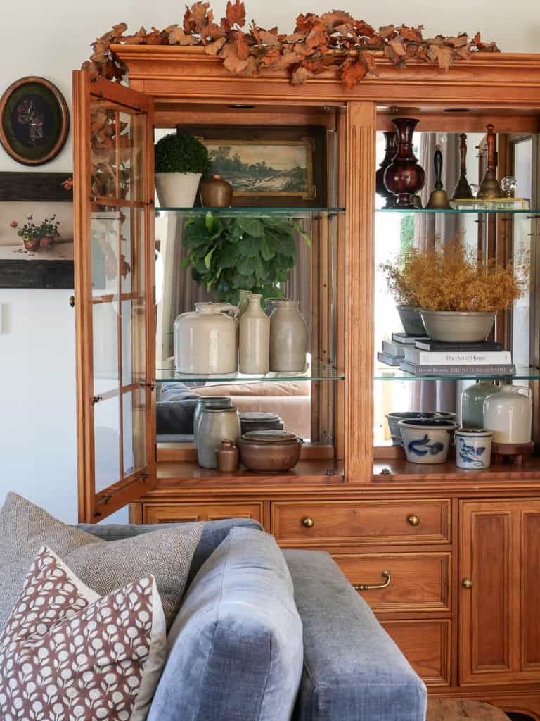 Fall decor inside a living room hutch.