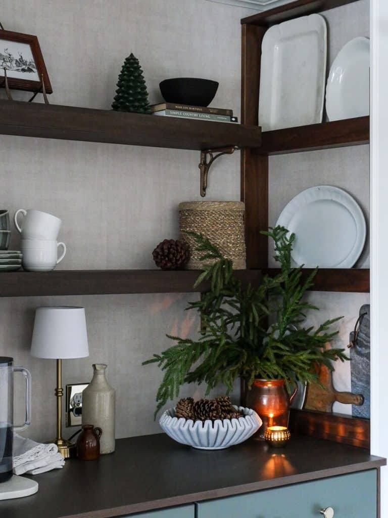Evergreen stems shown as cozy winter decor on a coffee bar.
