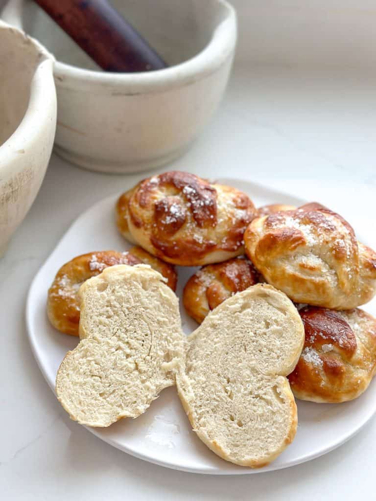 Baked sourdough discard pretzel buns on a plate.