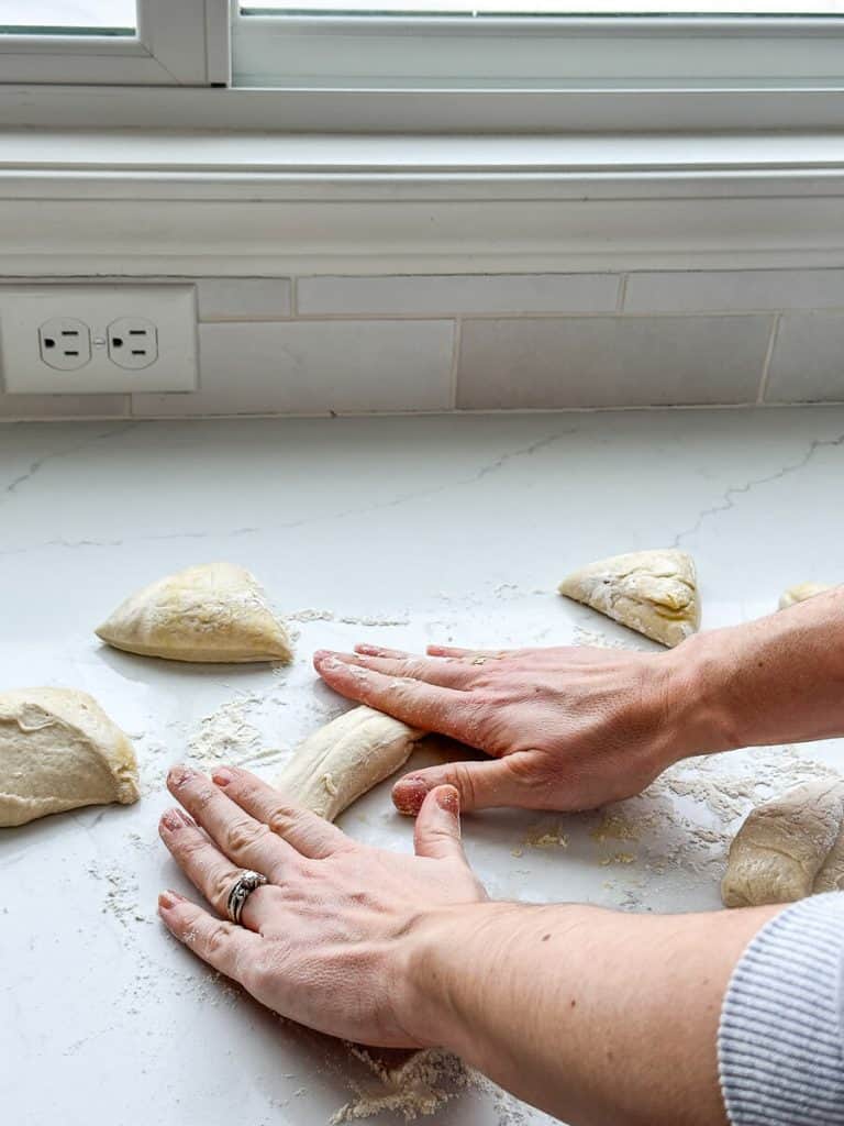 Rolling soft pretzel buns out.