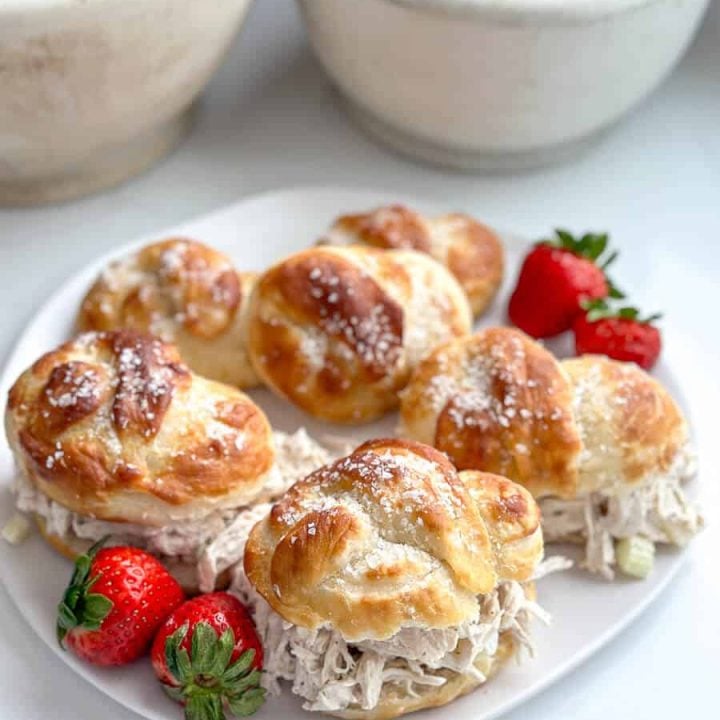 Soft pretzel buns on a plate with strawberries.