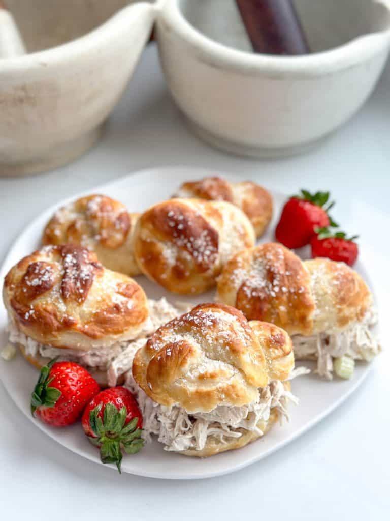 Soft pretzel buns on a plate with strawberries.