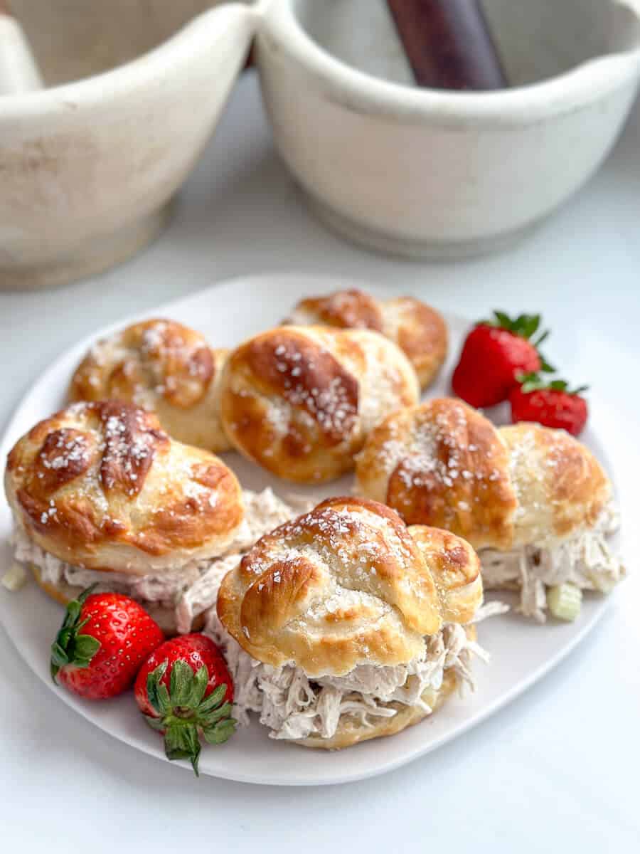 Soft pretzel buns on a plate with strawberries.