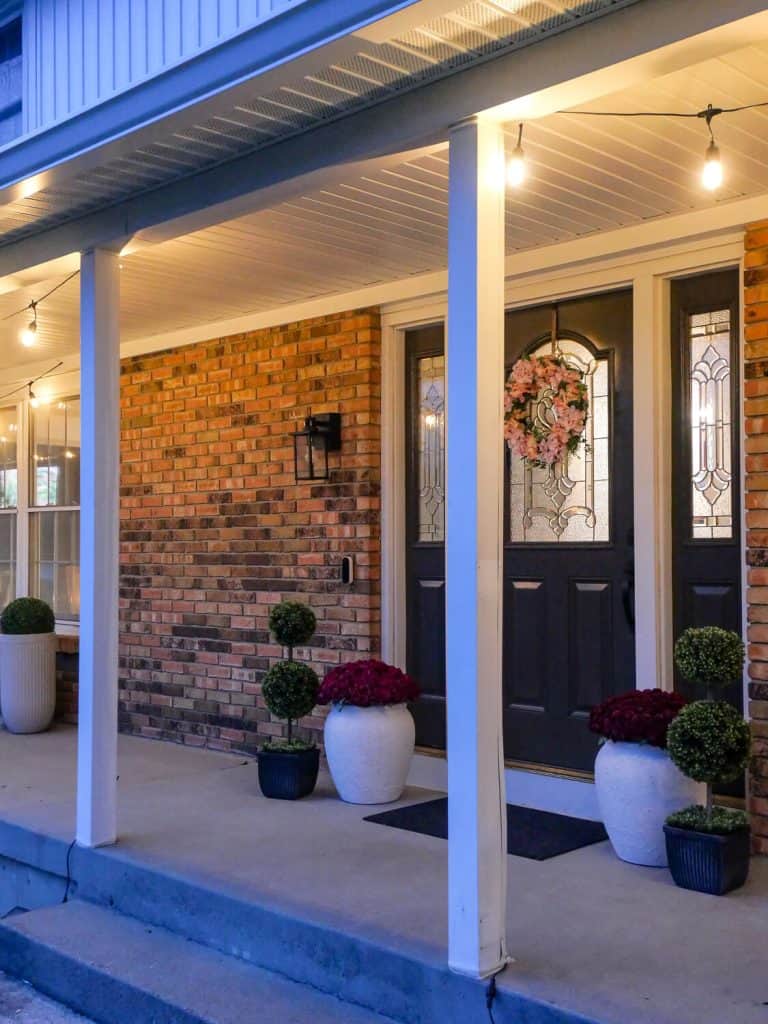 Cafe string lights on a front porch decorated for spring.