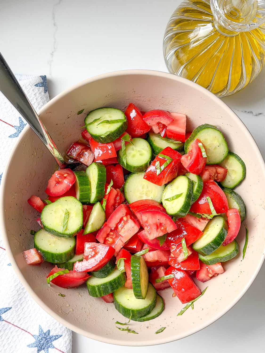 Cut up marinated tomatoes and cucumbers in a bowl.
