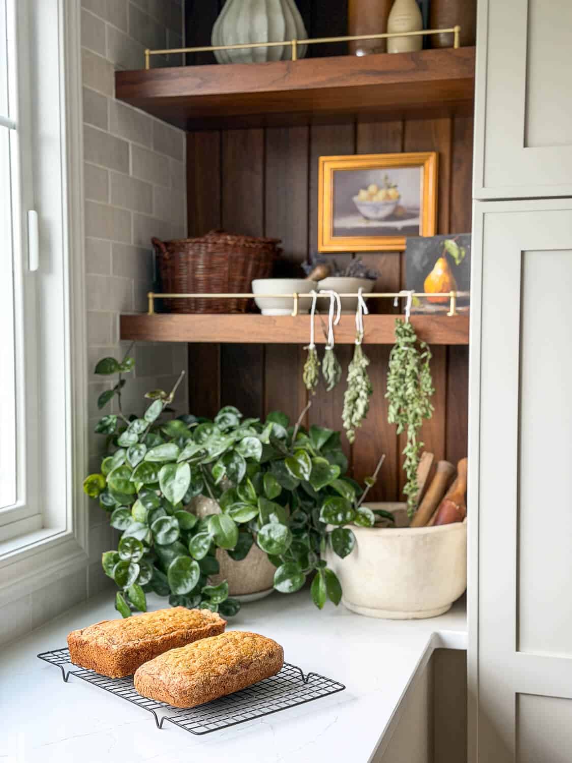 Walnut kitchen shelves with bread and drying herbs.